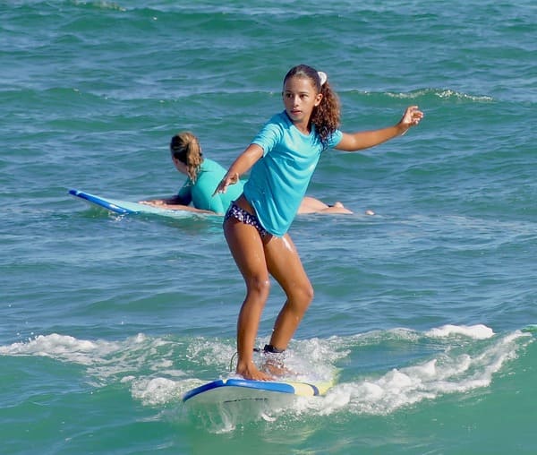 Jeune fille surfant une vague